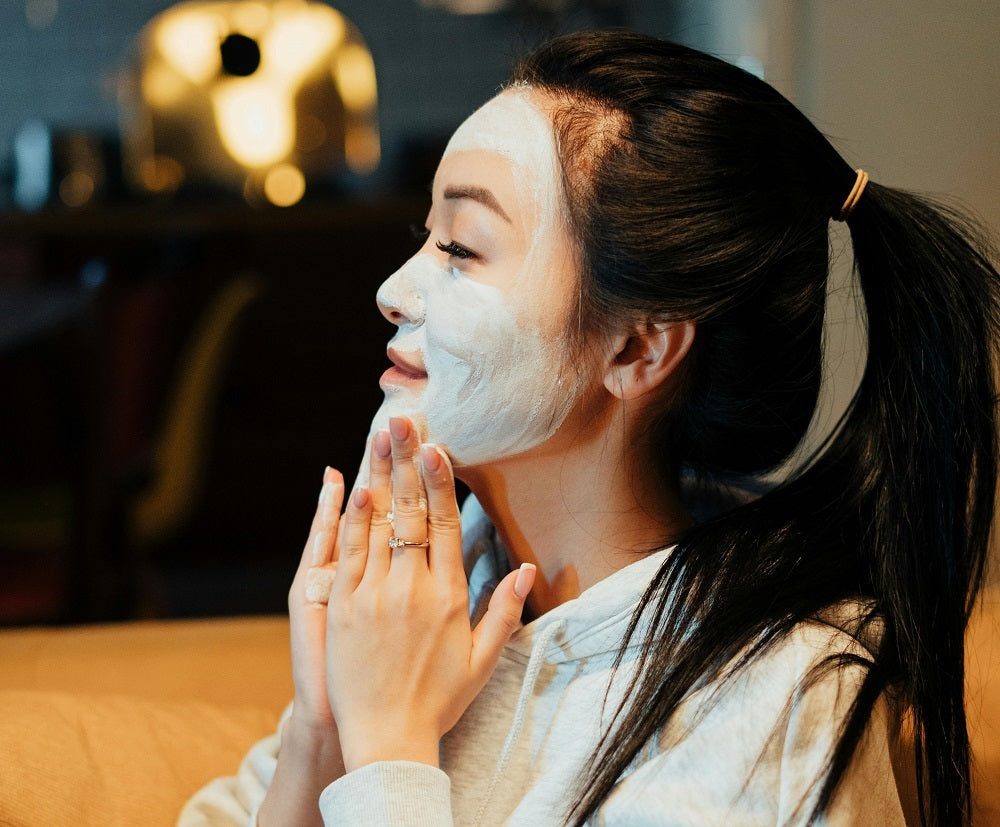 Woman applying botanical skincare mask at home